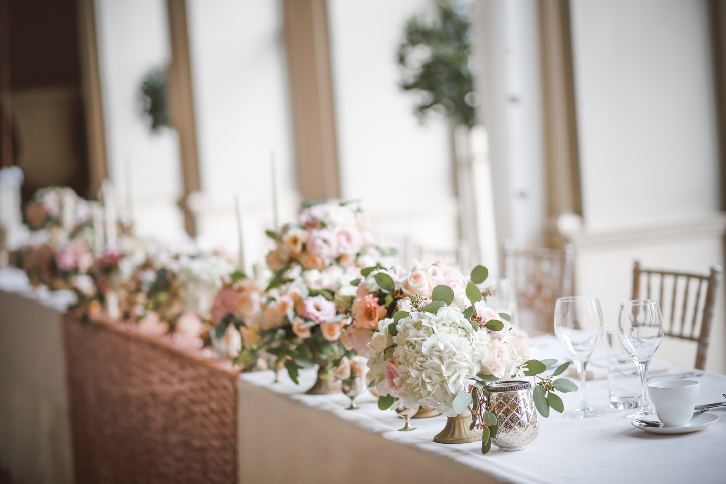 Elegante mesa de recepción de bodas decorada con centros florales y velas.