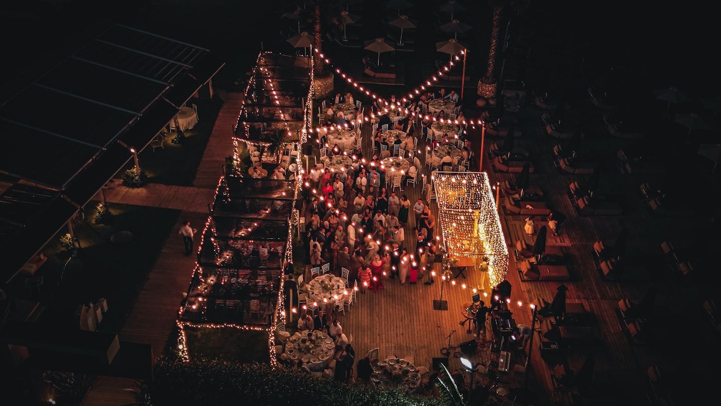 Gente celebrando en una terraza de madera con luces.