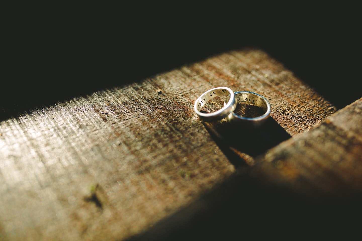 Dos anillos de boda plateados sobre una superficie de madera.